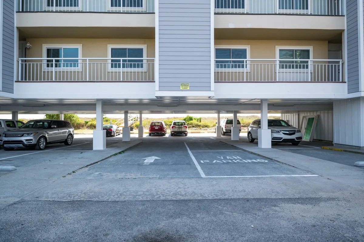 An exterior shot of the building’s parking area, with clearly visible parking spaces, vehicles, and the building’s facade. The environment appears safe and well-maintained.